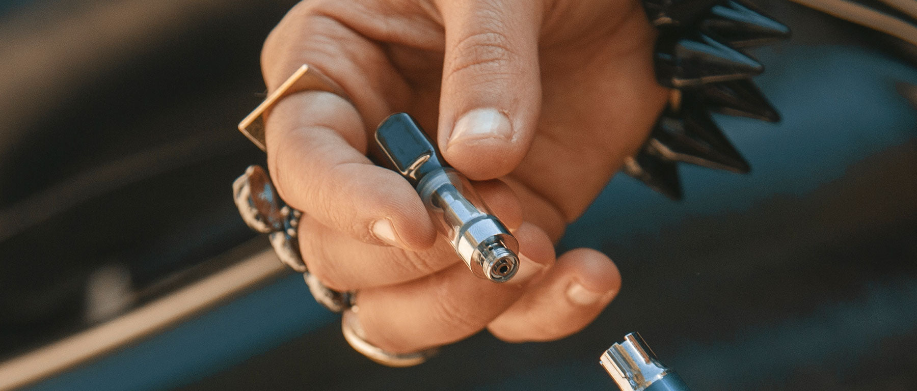 Man with rings holding a Cartridge Oil Replacement part outside near vehicle 