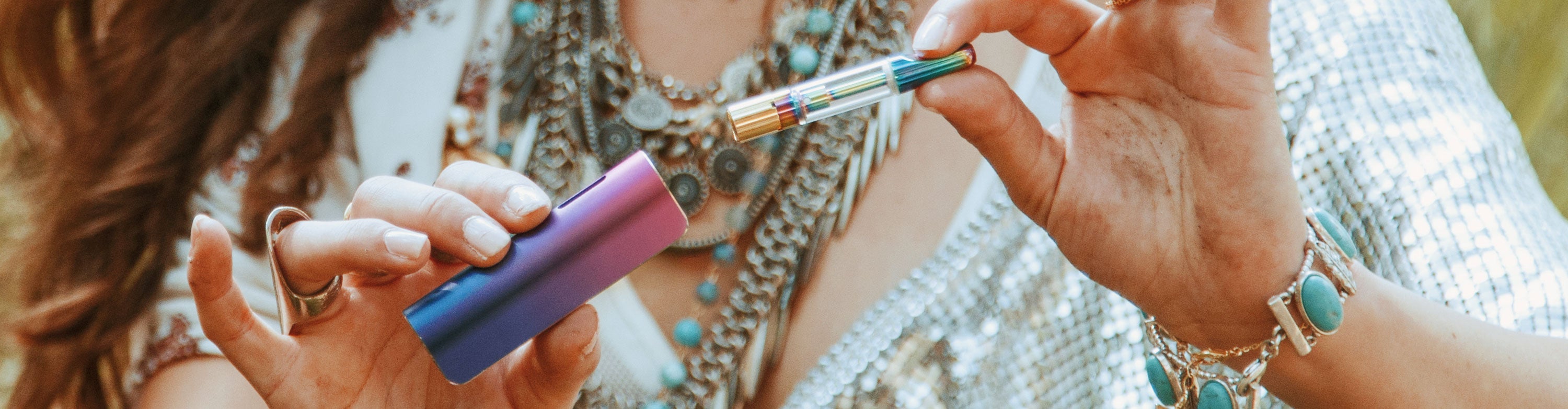 Woman with jewelry holding Exxus Snap VV with cartridge apart in front of meadow