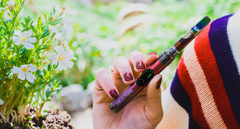 Woman holding Exxus TUNL near sprouting spring flowers on a trail