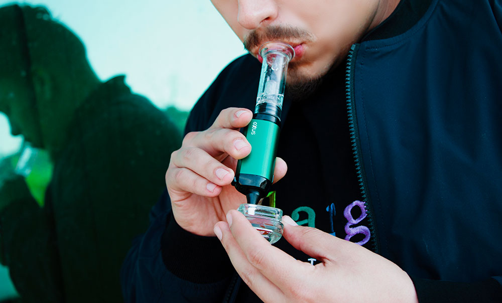 Person holding a teal Exxus VRS concentrate vaporizer