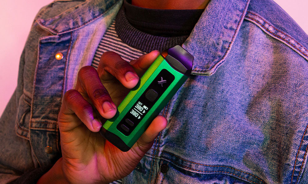 Person holding a green Exxus Mini Plus vaporizer