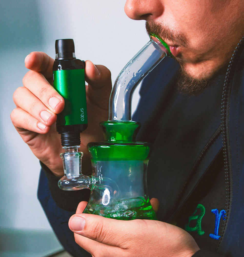 Person holding a green Exxus VRS with a water pipe attachment