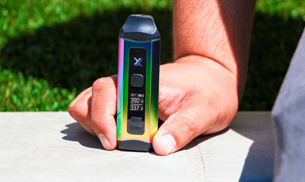 Man sitting next to his Exxus Mini Plus dual use vaporizer outside