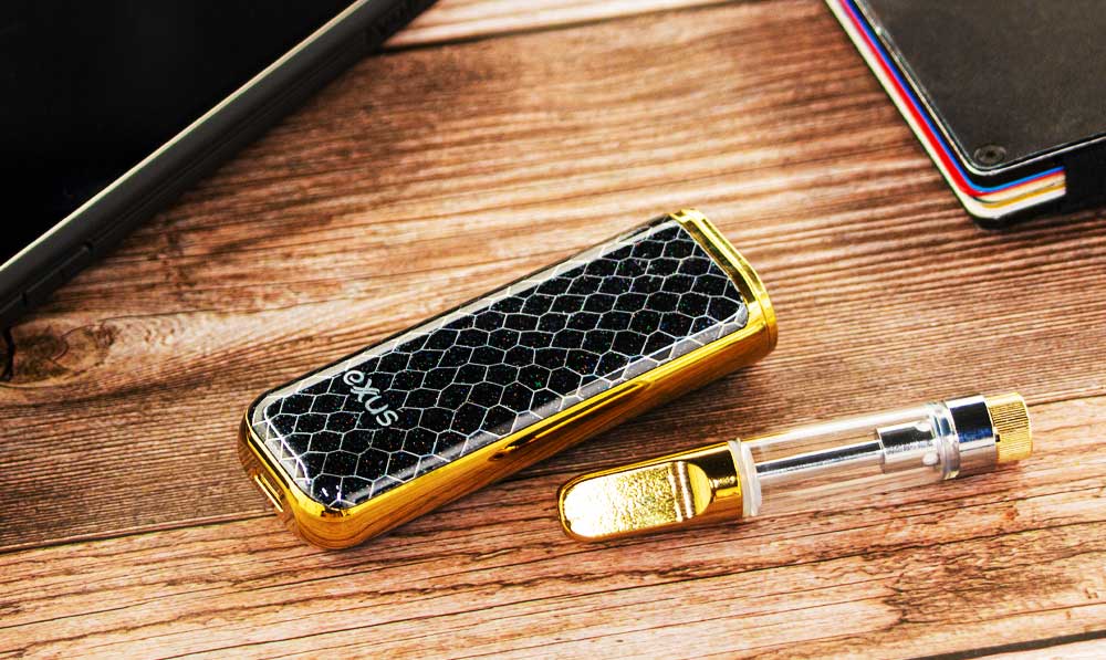 Exxus MiNovo resting on wooden desk near iPhone and empty cartridge