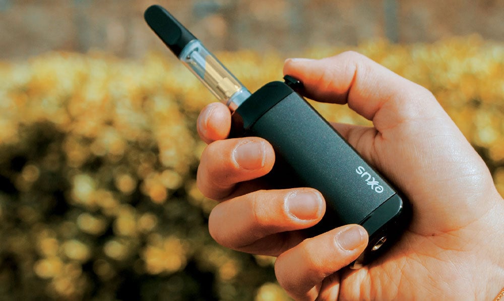 Exxus VRS in hand in front of series of bushes