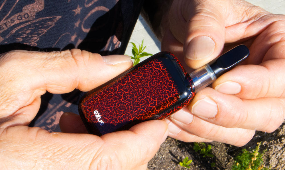 Man pulling cartridge out of Exxus Rizo Black Red Crackle with natural lighting