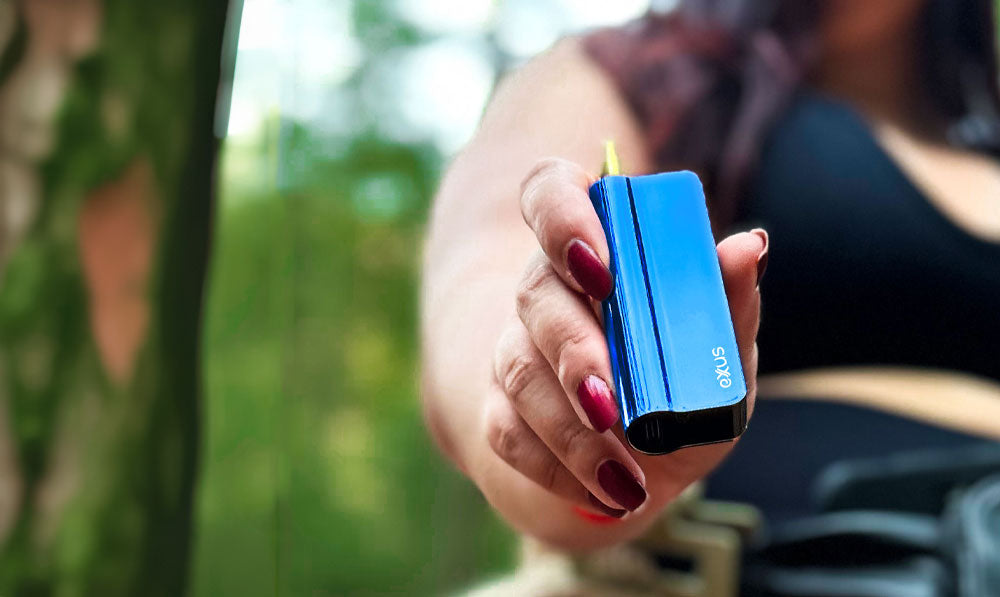 Woman holding Exxus Snap VV Pro in front of forest trees