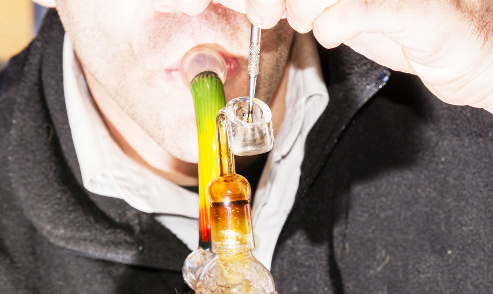 Man taking dab out of orange dab rig