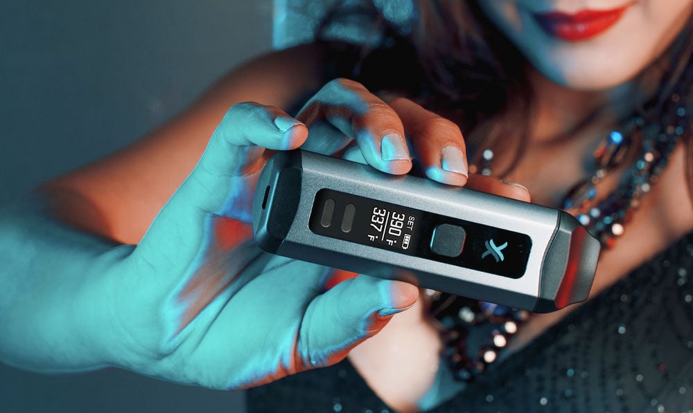 Woman in festive clothing holding Exxus Mini Plus under blue lighting
