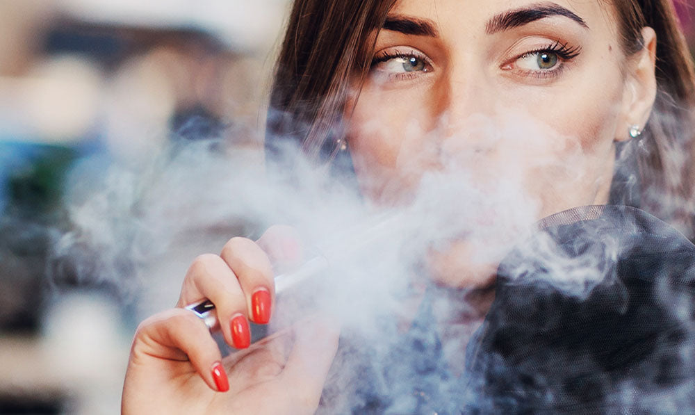 Woman vaping large cloud at a table