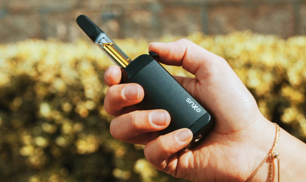 Person holding a green Exxus VRS in cartridge mode near foliage