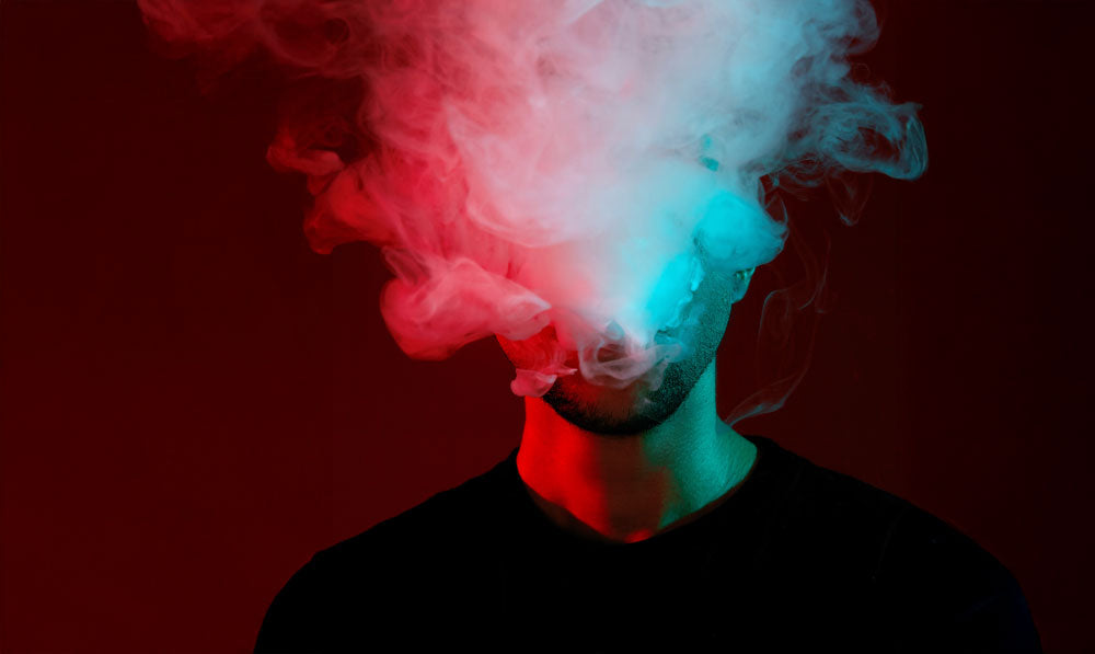 Man vaping in front of red studio background