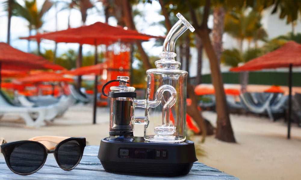 Exxus Go Plus resting on beach table with sunglasses nearby