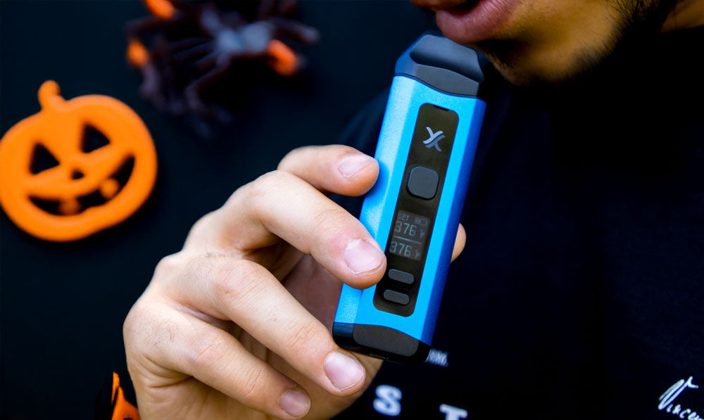 Man holding Exxus Mini Plus with Halloween decorations behind him