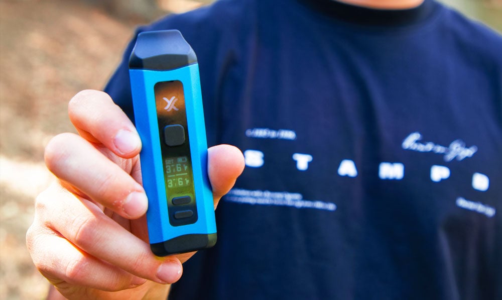 Person holding a blue Exxus Mini Plus vaporizer