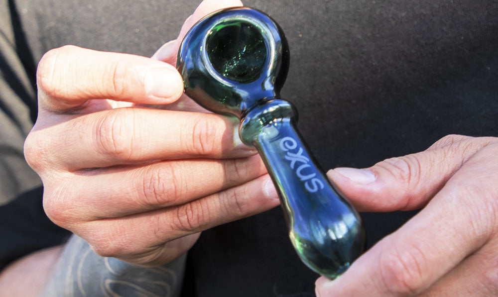 Close up of a person holding an Exxus Wand glass pipe