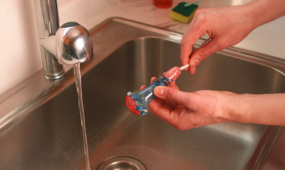 Person cleaning hand pipe over sink