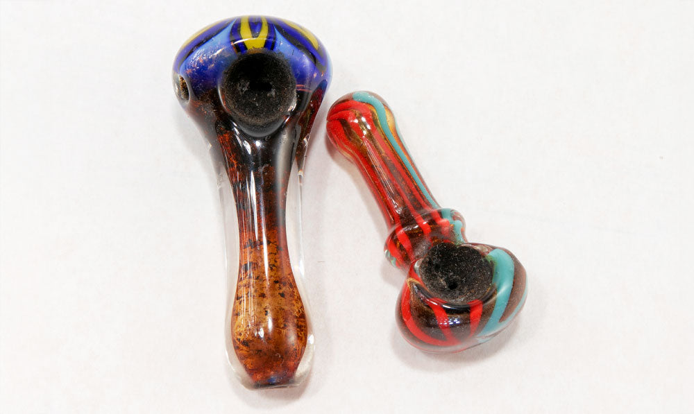Two used hand pipes on white surface