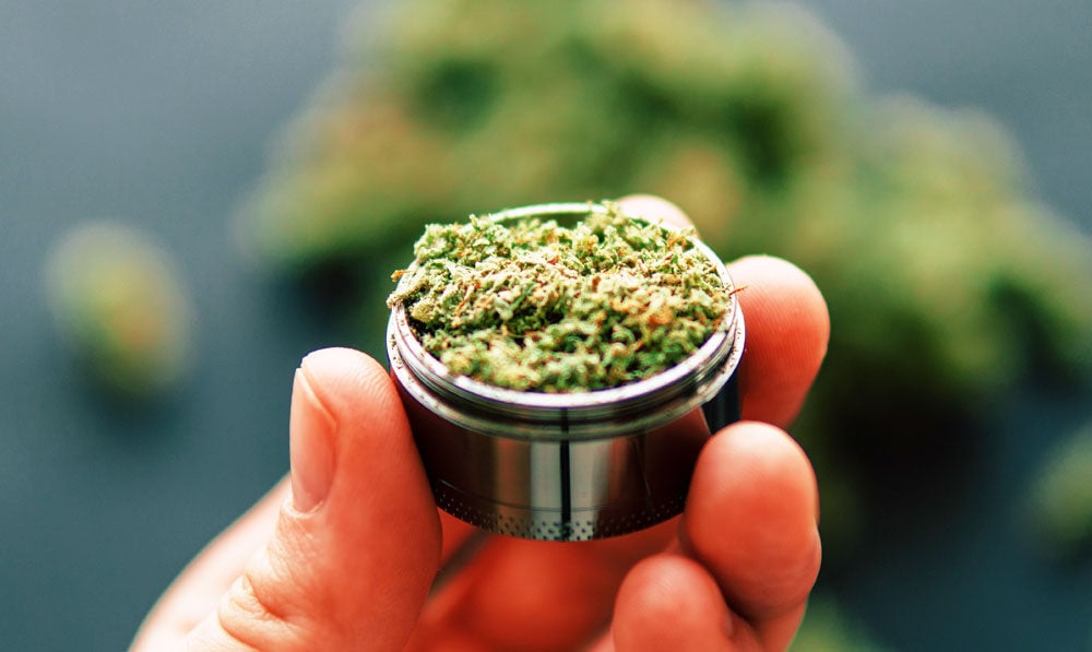 Hand holding herbs inside of a grinder