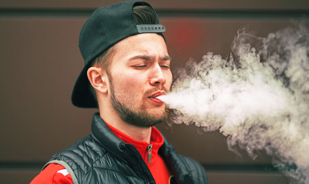 Man vaping in front of wall