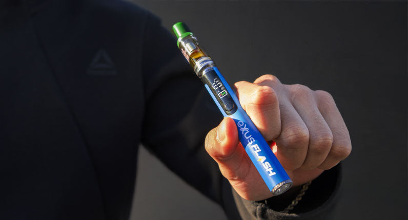 Person holding a blue Exxus Flash cartridge vaporizer with a cartridge attached