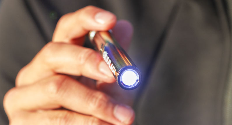 Hand holding an Exxus Flash cartridge vaporizer with its flashlight lit